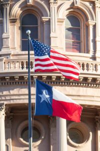 The U.S. and Texas flag flying over the Texas state Capitol.